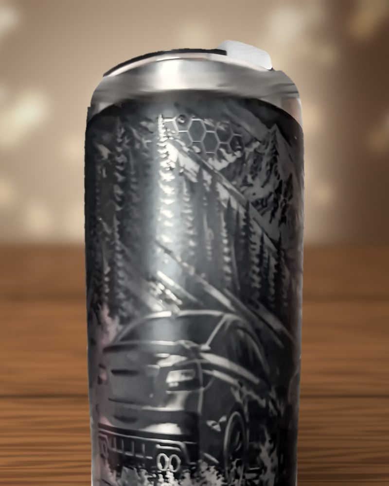 Black tumbler laser-engraved with pine trees, mountains, a honeycomb pattern and the rear of a car